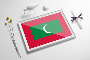 Maldives flag in wooden frame on table. White natural soft concept, national celebration theme.