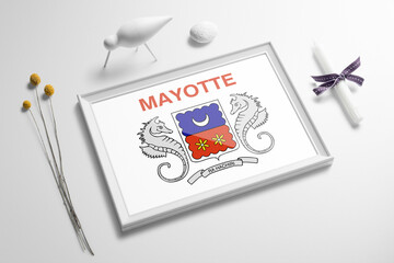 Mayotte flag in wooden frame on table. White natural soft concept, national celebration theme.