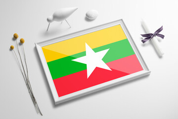 Myanmar flag in wooden frame on table. White natural soft concept, national celebration theme.