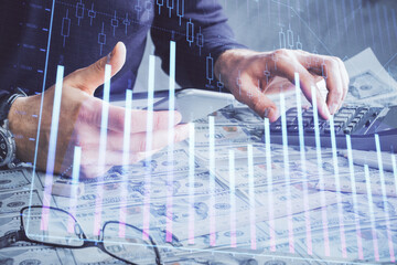 Double exposure of man's hands holding and using a digital device and forex graph drawing. Financial market concept.