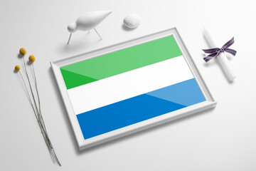 Sierra Leone flag in wooden frame on table. White natural soft concept, national celebration theme.