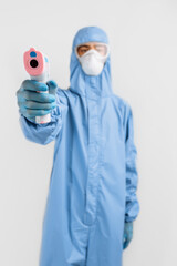 male doctor in a protective suit from the coronavirus, a medical mask glasses and gloves, uses an...