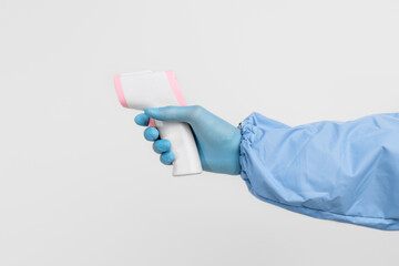 Close-up of a doctor's hand, in a protective suit and gloves, measuring the temperature with an...