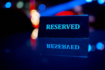 A sign is reserved on a reflective surface in a nightclub with a beautiful side