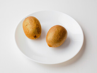 close-up of two fresh kiwi on a white plate and white background.