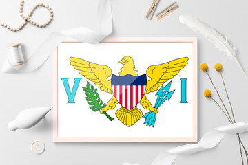 United States Virgin Islands flag in wooden frame on white creative background. White theme, feather, daisy, button, ribbon objects.