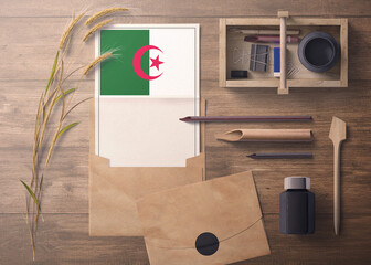 Algeria invitation, celebration letter concept. Flag with craft paper and envelope. Retro theme with divide, ink, wooden pen objects.
