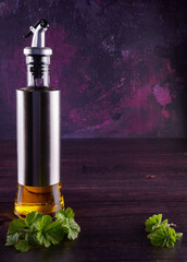 Olive oil drizzler with herbs on wooden table