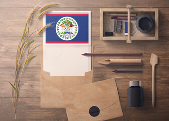 Belize invitation, celebration letter concept. Flag with craft paper and envelope. Retro theme with divide, ink, wooden pen objects.