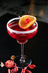 Making cocktails at home like an expert nightclub barman. Fresh and juicy colorful homemade cocktails garnished with berries, orange, cherry  on dark background.