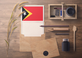 East Timor invitation, celebration letter concept. Flag with craft paper and envelope. Retro theme with divide, ink, wooden pen objects.