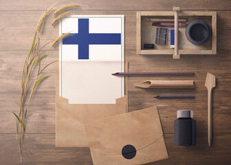 Finland invitation, celebration letter concept. Flag with craft paper and envelope. Retro theme with divide, ink, wooden pen objects.