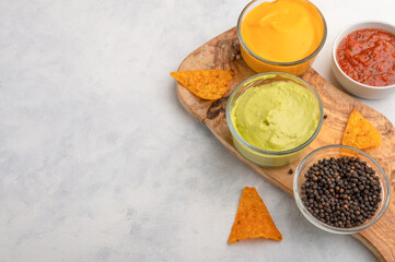 Chips and snacks with salsa and sauces on a light background, snacks for the evening