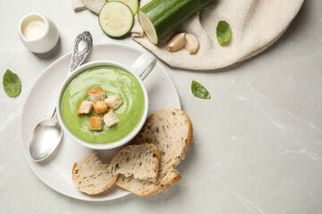 Tasty homemade zucchini cream soup served on light table, flat lay