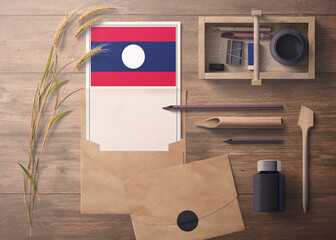 Laos invitation, celebration letter concept. Flag with craft paper and envelope. Retro theme with divide, ink, wooden pen objects.