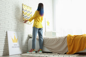 Decorator hanging picture on white brick wall. Children's room interior design