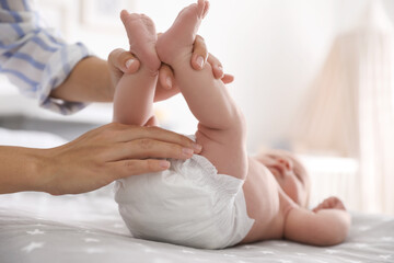 Mother changing her baby's diaper on bed - obrazy, fototapety, plakaty