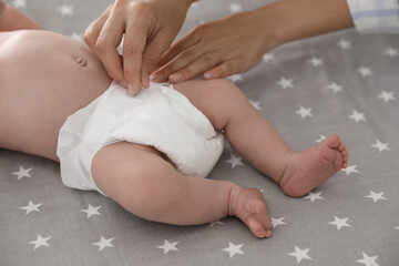 Mother changing her baby's diaper on bed, closeup