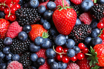 Mix of different ripe tasty berries as background, top view