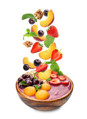 Acai berries and other ingredients falling into bowl on white background