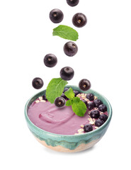 Acai berries and mint falling into bowl on white background