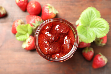 Delicious pickled strawberry jam and fresh berries on wooden table, flat lay