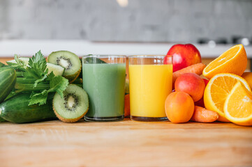 Orange juice and green juice with fresh and raw fruit in the background