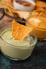 Chips and snacks with avocado and dip sauce, close-up top view