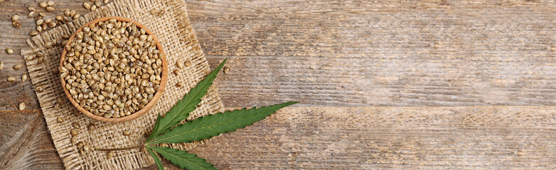 Bowl of hemp seeds and space for text on wooden background, top view. Banner design