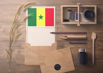 Senegal invitation, celebration letter concept. Flag with craft paper and envelope. Retro theme with divide, ink, wooden pen objects.