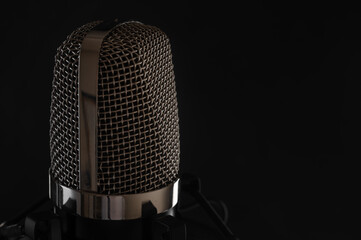Studio professional microphone close-up on a black background for an inscription. Vocal and voice recording, work with sound recording