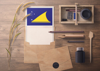 Tokelau invitation, celebration letter concept. Flag with craft paper and envelope. Retro theme with divide, ink, wooden pen objects.