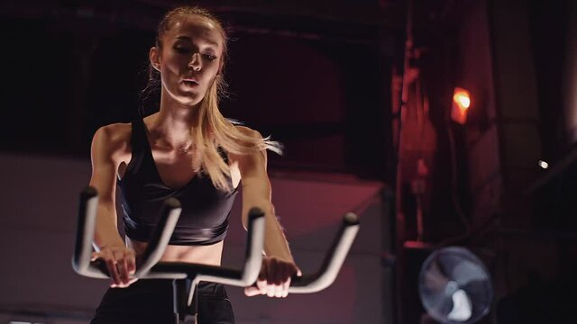 Young Fit Sporty Blone Girl Exercising on a Bike at Gym