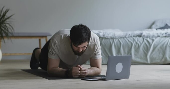 Bearded guy using stopwatch on phone, standing in plank