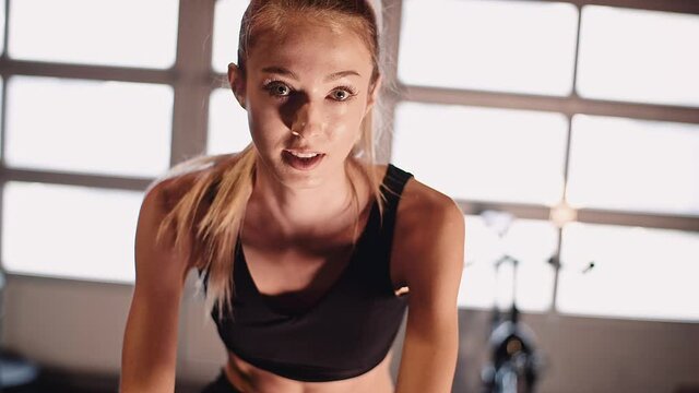 Young Fit Sporty Blone Girl Exercising on a Bike at Gym