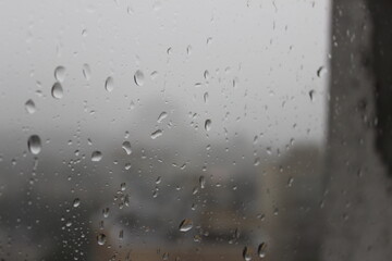 Natural Pattern of raindrops isolated on cloudy background. Rainy day. Raindrops on window glass. Close up shot on droplets of the rain on window glass.