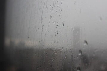 Natural Pattern of raindrops isolated on cloudy background. Rainy day. Raindrops on window glass. Close up shot on droplets of the rain on window glass.