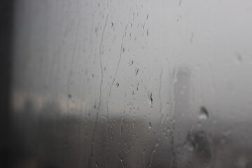 Natural Pattern of raindrops isolated on cloudy background. Rainy day. Raindrops on window glass. Close up shot on droplets of the rain on window glass.
