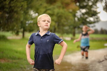 Playful boy making funny pose near flooded creek