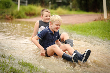 Naklejka na ściany i meble Happy kids playing in floodwater on rainy day