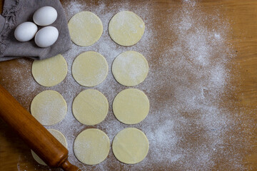 
tapas of empanadas or crepes on a table with a stick to knead eggs and flour, ingredients for a preparation.