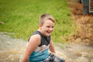 Happy boy playing in floodwater on rainy day