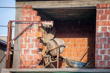Concrete mixer ready for use on a construction site of a red brick house in a residential district...
