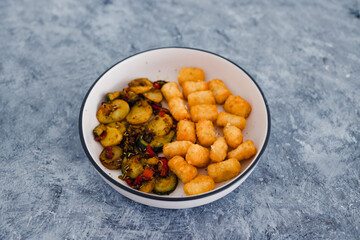 plant-based food, sauteed mediterranean vegetables with soy sauce and wir fried potato royals