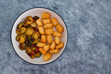 plant-based food, sauteed mediterranean vegetables with soy sauce and wir fried potato royals
