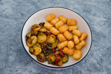plant-based food, sauteed mediterranean vegetables with soy sauce and wir fried potato royals