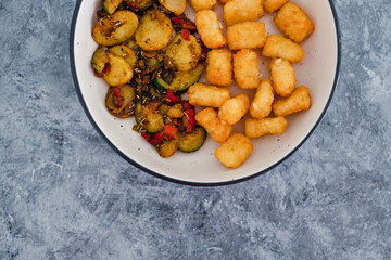 plant-based food, sauteed mediterranean vegetables with soy sauce and wir fried potato royals