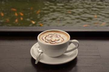 Decorative cup of freshly expressed coffee with faded gold fish in the background