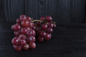 Bunch of red grape isolated on dark wood background