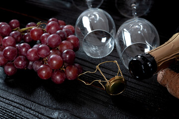 Bunch of red grapes and champagne glass with dark wood background